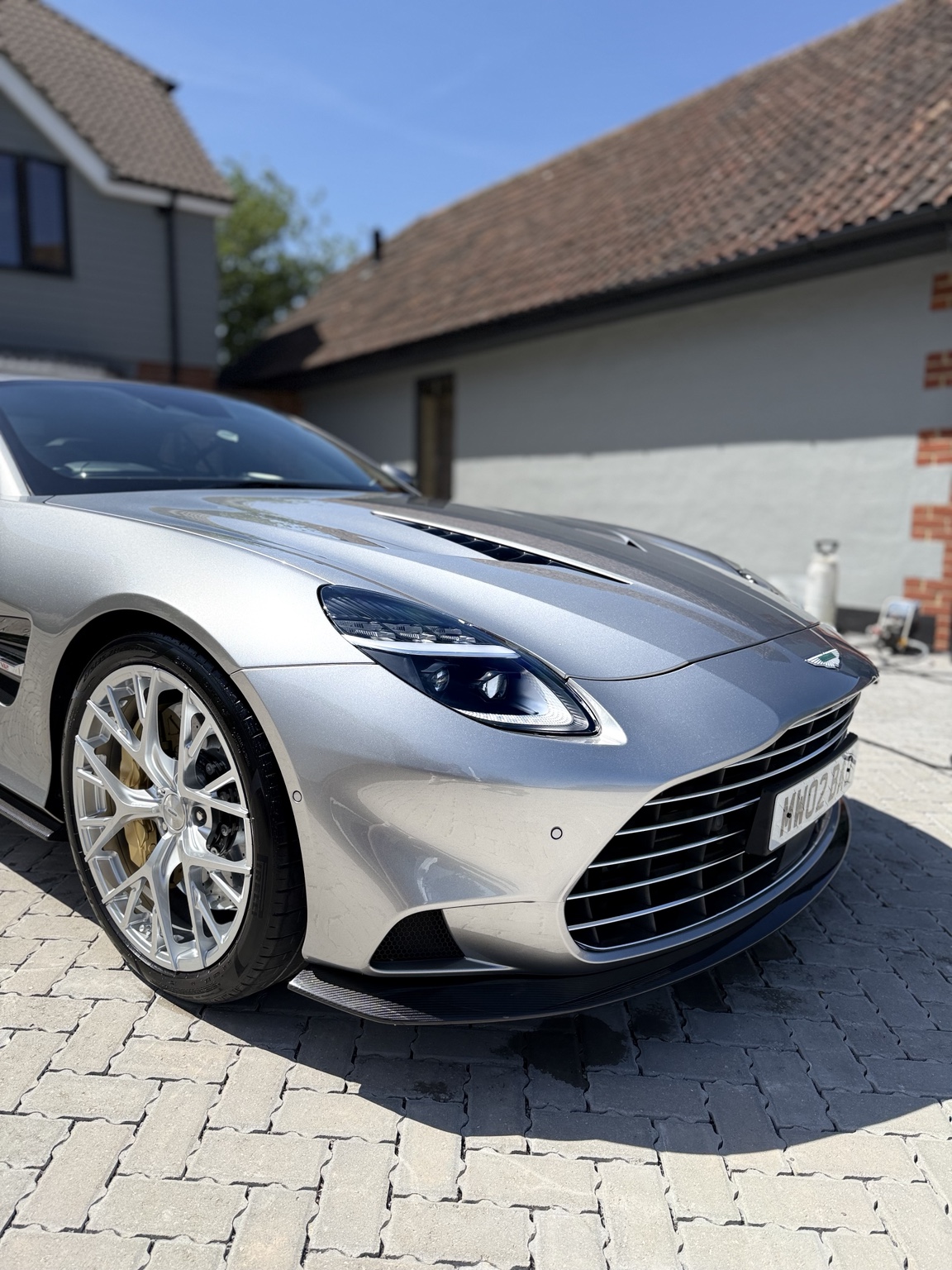 Front quarter of a silver Aston Martin in sunlight